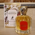Maison Alhambra La Rouge Baroque 100ml — A perfume bottle with yellow liquid and a red label, next to its decorative box with gold and red leaf patterns and a deer logo. | Maison Alhambra La Rouge Baroque 100ml — Botol minyak wangi dengan cecair kuning dan label merah, bersebelahan dengan kotak hiasannya dengan corak