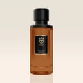 Bujairami Legacy by Bujairami 100ml Extrait — An amber-colored glass perfume bottle with a black cap and a black label featuring gold text and a gold crest. | Bujairami Legacy by Bujairami 100ml Extrait — Botol kaca berwarna ambar dengan penutup hitam dan label hitam yang menampilkan teks emas dan lambang emas.
