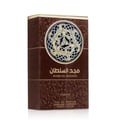 Asdaaf Majd Al Sultan — A dark brown velvet-textured perfume bottle with a gold and black cap stands next to its matching brown box, both featuring a circular Celtic knot design. | Asdaaf Majd Al Sultan — Botol minyak wangi bertekstur baldu coklat gelap dengan penutup emas dan hitam berdiri di sebelah kotak coklat
