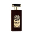 Asdaaf Majd Al Sultan — A dark brown velvet-textured perfume bottle with a gold and black cap stands next to its matching brown box, both featuring a circular Celtic knot design. | Asdaaf Majd Al Sultan — Botol minyak wangi bertekstur baldu coklat gelap dengan penutup emas dan hitam berdiri di sebelah kotak coklat