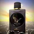 Lattafa Malik Al Tayoor Concentrated 100ml — Black perfume bottle and its black textured box with a golden eagle emblem and Arabic text, set against a white background. | Lattafa Malik Al Tayoor Concentrated 100ml — Botol minyak wangi hitam dan kotaknya yang bertekstur hitam dengan lambang helang emas dan teks Arab