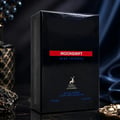 Maison Alhambra Moondrift Blue Intense 100ml Alhambra — A blue glass perfume bottle with a red label and a matching blue box with a red label, both featuring a deer logo and text. | Maison Alhambra Moondrift Blue Intense 100ml Alhambra — Botol kaca biru dengan label merah dan kotak biru sepadan dengan label merah