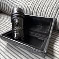 Lattafa Musamam Black Intense — A black snake coiled around the cap of a dark glass perfume bottle, resting on a textured black stand with a snake-skin pattern. | Lattafa Musamam Black Intense — Seekor ular hitam melingkar di sekeliling penutup botol minyak wangi kaca gelap, diletakkan di atas tapak hitam bertekstur