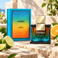 Armaf Ombre Fresh by Armaf 100ml EDP Unisex — Glass perfume bottle with gradient amber-to-teal liquid, gold cap, on a black speckled base, next to its blue gradient box.