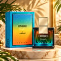 Armaf Ombre Fresh by Armaf 100ml EDP Unisex — Glass perfume bottle with gradient amber-to-teal liquid, gold cap, on a black speckled base, next to its blue gradient box.