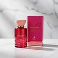 Maison Alhambra Papillon D'Or 100ml Maison Alhambra — A red glass perfume bottle with a pink cap sits next to its matching bright pink box, which features a gold butterfly design. | Maison Alhambra Papillon D'Or 100ml Maison Alhambra — Botol kaca merah dengan penutup merah jambu duduk bersebelahan dengan kotak merah