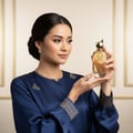 Perfume bottle with gold cap and intricate design on a white background