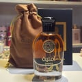 Amnia perfume bottle with brown drawstring bag and black card on a shelf background