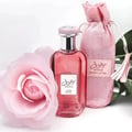 Pink perfume bottle with a pink drawstring bag and a pink rose on a light gray background