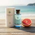 Men’s perfume bottle and box on beach wood table in Malaysia with grapefruit slice and ocean view – summer fresh fragrance