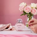 Perfume bottle labeled 'Charm' by Lalique on a pink fabric background