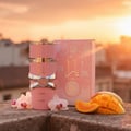 Woman perfume bottle on balcony at golden hour with tangerine sky and orchid petals – Yara vanilla tropical note