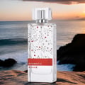 Perfume bottle labeled 'Aromatic Rouge' on a rocky surface with a sunset over water background
