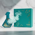 Perfume bottle broken, icy mint fog emerging; studio on white marble Malaysia — clear bottle and box, cinematic lighting.