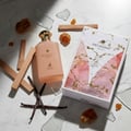 Decadent Dream perfume bottle and packaging on a patterned fabric background