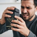 Person holding a black Kismet Magic perfume bottle