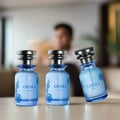 Three blue perfume bottles with silver caps on a reflective surface against a light blue background.