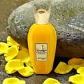 Yellow pulp perfume bottle with gold cap on a stone surface with yellow petals