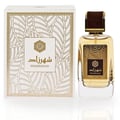 Ard Al Zaafaran Shahrazad Eau De Parfum — A white box with gold leaf pattern and a clear glass perfume bottle with gold accents and amber liquid, set against a white background. | Ard Al Zaafaran Shahrazad Eau De Parfum — Kotak putih dengan corak daun emas dan botol minyak wangi kaca jernih dengan aksen emas dan