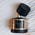 Lattafa Tamima — Black perfume bottle with gold label and black cap, next to a black product box with gold Arabic script and text | Lattafa Tamima — Botol minyak wangi hitam dengan label emas dan penutup hitam, bersebelahan kotak produk hitam dengan skrip Arab emas dan teks