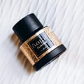 Lattafa Tamima — Black perfume bottle with gold label and black cap, next to a black product box with gold Arabic script and text | Lattafa Tamima — Botol minyak wangi hitam dengan label emas dan penutup hitam, bersebelahan kotak produk hitam dengan skrip Arab emas dan teks