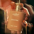 Paris Corner Taskeen Caramel Cascade 100ml — A rectangular perfume box with a marble-like pattern in beige and pink hues, accented with gold glitter stripes and gold text. | Paris Corner Taskeen Caramel Cascade 100ml — Peti minyak wangi berbentuk segi empat dengan corak seperti marmar dalam warna beige dan merah