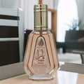 Ard Al Zaafaran Yara Eau De Parfum 50ml — Pink floral patterned box next to a faceted pale pink perfume bottle with a silver cap. | Ard Al Zaafaran Yara Eau De Parfum 50ml — Kotak bercorak bunga merah jambu di sebelah botol minyak wangi merah jambu pucat berfaset dengan penutup perak.