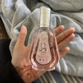 Ard Al Zaafaran Yara Eau De Parfum 50ml — Pink floral patterned box next to a faceted pale pink perfume bottle with a silver cap. | Ard Al Zaafaran Yara Eau De Parfum 50ml — Kotak bercorak bunga merah jambu di sebelah botol minyak wangi merah jambu pucat berfaset dengan penutup perak.