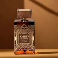 Zimaya Amber Is Great Eau De Parfum 100ml — A brown textured box with gold geometric art deco design stands next to a rectangular glass perfume bottle with a ribbed brown cap and gold geometric art deco design. The bottle contains amber-colored liquid. | Zimaya Amber Is Great Eau De Parfum 100ml — Kotak bertekstur